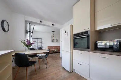 a kitchen with white cabinets and a table with chairs at Resort Stories Išskirtiniai 7 vietų apartamentai Birštone in Birštonas