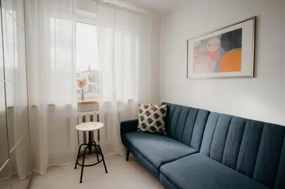 a living room with a blue couch and a window at Resort Stories Išskirtiniai 7 vietų apartamentai Birštone in Birštonas