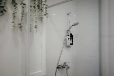 a shower with a hose attached to a wall at Resort Stories Išskirtiniai 7 vietų apartamentai Birštone in Birštonas