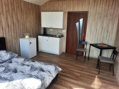 a bedroom with a bed and a table and a kitchen at Vipoilsis Namelis N1 in Čekoniškės