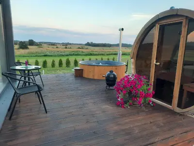 a wooden deck with a hot tub and flowers at Vipoilsis Namelis N1 in Čekoniškės