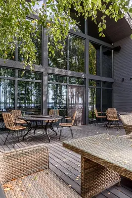 a patio with a table and chairs and windows at Molėtairesort in Molėtai