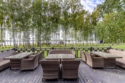 a wooden deck with tables and chairs in a park at Molėtairesort in Molėtai