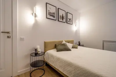 a white bedroom with a bed and two tables at Modern 2 bedroom Vytenio apartment in city centre I Self check-in in Vilnius