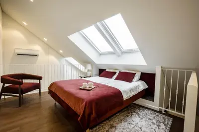 a attic bedroom with a bed and a chair at Loft 27 in Kaunas