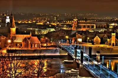 a city with a bridge over a river at night at Loft 27 in Kaunas
