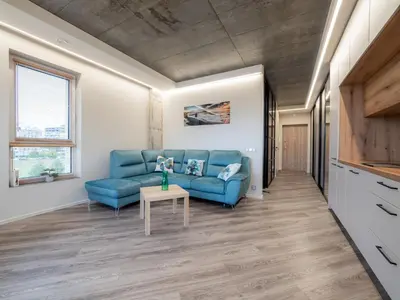 a living room with a blue couch and a table at Cozy Apartment Vilnius in Vilnius
