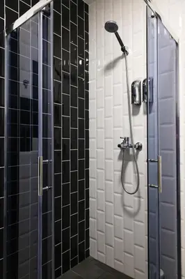 a bathroom with a shower with black and white tiles at Romantic Room Šiauliai in Šiauliai