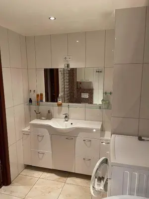 a white bathroom with a sink and a mirror at Dainai Apartments in Šiauliai