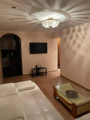 a living room with a white couch and a tv at Dainai Apartments in Šiauliai