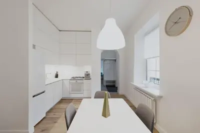 a white kitchen with a table and chairs and a clock at Vilnius Old Town Apt Subacius 3. Free Parking in Vilnius