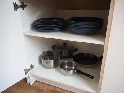 a cupboard with pots and pans and plates at Cozy city center apartment in Visaginas