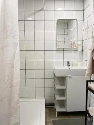a white bathroom with a sink and a mirror at Cozy city center apartment in Visaginas