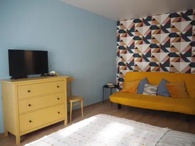 a bedroom with a yellow couch and a tv on a dresser at Cozy city center apartment in Visaginas