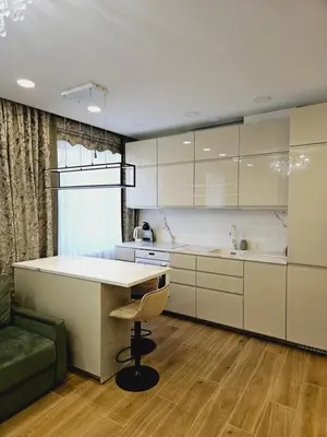 a kitchen with white cabinets and a table and a chair at Uzupis Riverside Apartment in Vilnius