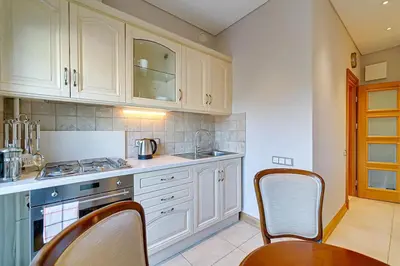 a kitchen with white cabinets and a table and chairs at Arena Park Apartment in Kaunas
