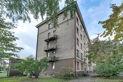 a large brick building with trees in front of it at Arena Park Apartment in Kaunas