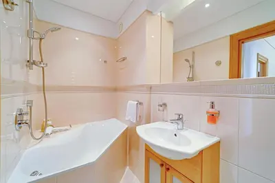 a white bathroom with a sink and a shower at Arena Park Apartment in Kaunas
