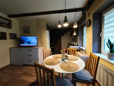 a dining room with a table and chairs and a television at Cosy studio apartment with the garden in Druskininkai