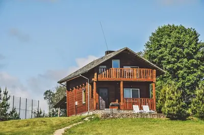 a wooden house with a deck on a hill at Svajonių Dvaras in Balninkai