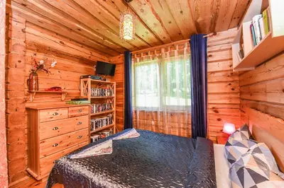 a log cabin bedroom with a bed and a window at Svajonių Dvaras in Balninkai