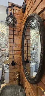 a bathroom with a mirror on a brick wall at Studio apartment in Jeruzalė in Vilnius