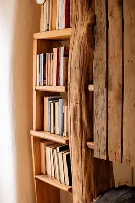 a wooden book shelf with books on it at Kupolinis namelis in Kilova II