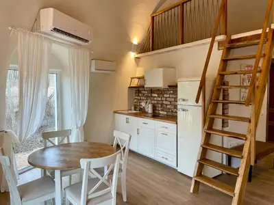 a kitchen with a table and a staircase in a room at Kupolinis namelis in Kilova II