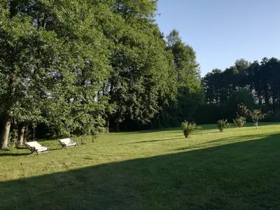 a park with two park benches in the grass at Lakeshore house in Dvarčėnai