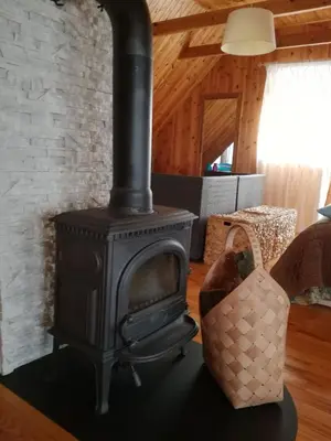 a black stove in a living room with a couch at Lakeshore house in Dvarčėnai