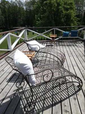 a deck with chairs and tables on a wooden deck at Lakeshore house in Dvarčėnai
