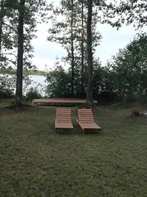two benches sitting in the grass next to a lake at Lakeshore house in Dvarčėnai