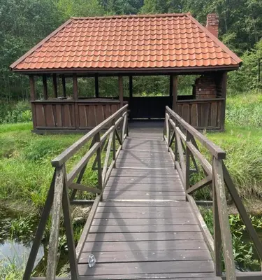 a wooden bridge leading to a gazebo with an orange roof at Forest House in Pašvinės