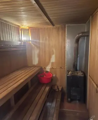 a small wooden sauna with a red bucket in it at Forest House in Pašvinės