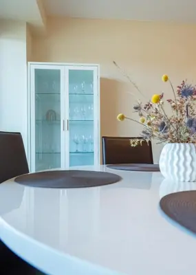 a white table with a vase of flowers on it at Aqua House in Druskininkai