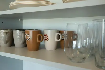 a row of coffee cups and wine glasses on a shelf at Aqua House in Druskininkai