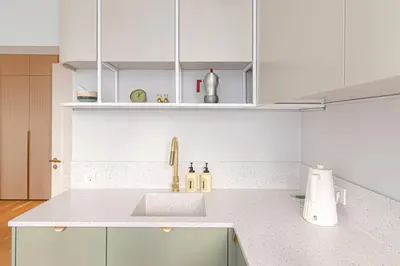 a white kitchen with a sink and white cabinets at #stayhere - Authentic & Artsy Studio in Heart of Vilnius Old Town in Vilnius