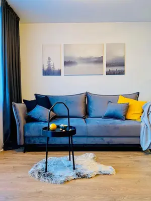 a blue couch with a table in a living room at Alyvų tako studija in Alytus