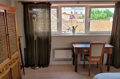 a bedroom with a desk and a window and a table at Meshka's Apartment in Vilnius