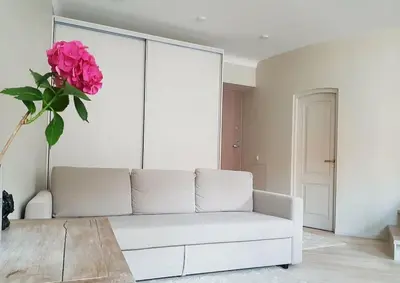 a living room with a white couch and a vase of pink flowers at Meshka's Apartment in Vilnius