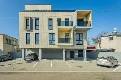 a building with two cars parked in a parking lot at Lovely Apartment with Private Terrace by URBAN RENT in Kaunas