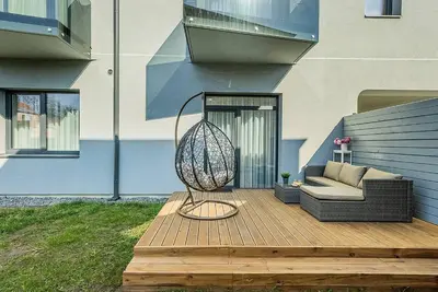 a patio with a swing and a couch on a wooden deck at Lovely Apartment with Private Terrace by URBAN RENT in Kaunas