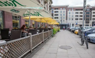people sitting at a restaurant under umbrellas on a sidewalk at Vilnius Centre Flat in Vilnius