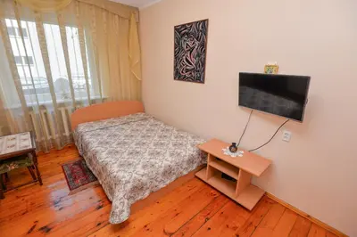 a small bedroom with a bed and a television at Poilsis prie Dineikos parko in Druskininkai