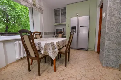 a dining room with a table and chairs and a kitchen at Poilsis prie Dineikos parko in Druskininkai