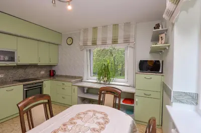 a kitchen with green cabinets and a table and a window at Poilsis prie Dineikos parko in Druskininkai