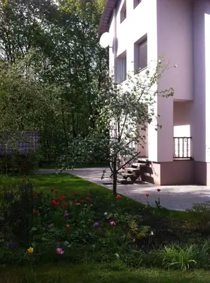 a garden in front of a building with flowers at Poilsis prie Dineikos parko in Druskininkai