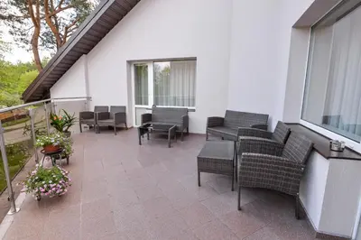 an outdoor patio with chairs and tables and windows at Poilsis prie Dineikos parko in Druskininkai