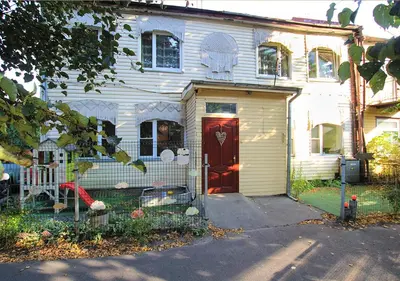 a white house with a red door and a fence at Authentic old studio house in Kaunas