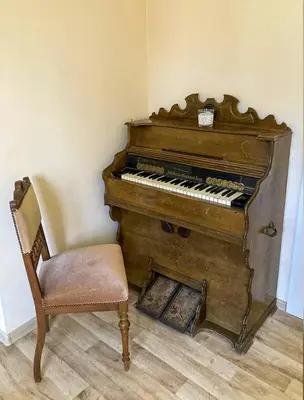 an old piano and a chair next to a wall at Authentic old studio house in Kaunas